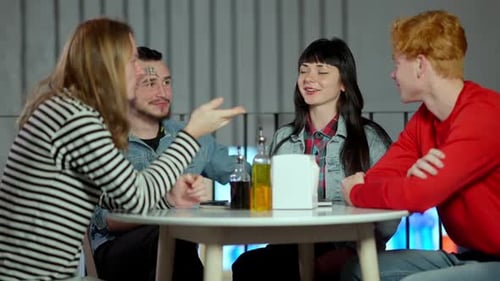 Group of Cheerful Relaxed Friends Sitting at Table in Cafe or Restaurant Talking and Smiling