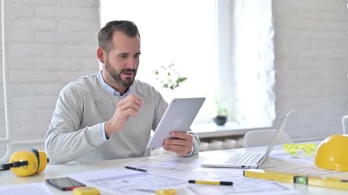 Young Architect Celebrating Success on Tablet in Office