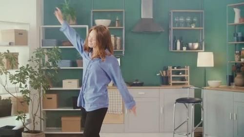 Enthusiastic Young Woman Dancing Freely in Kitchen