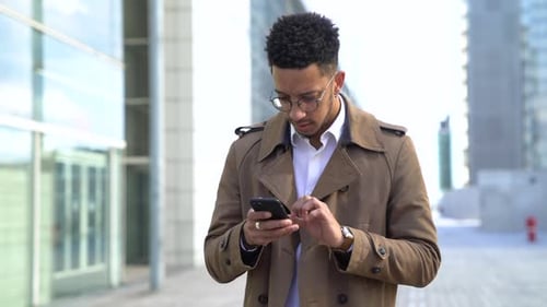 Young Man Using Phone on City Street