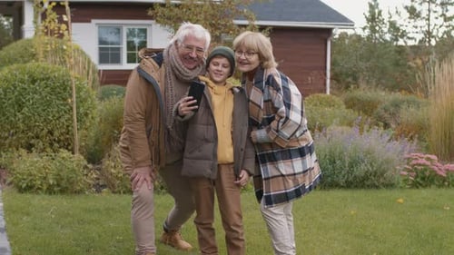 Grandparents and Grandson Take Selfie on Lawn
