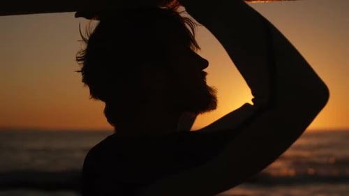 Mann spaziert mit Surfbrett am Strand