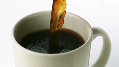 Black Coffee Being Poured into a White Mug
