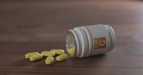 Vitamin C Pills Next to Bottle on Wooden Surface