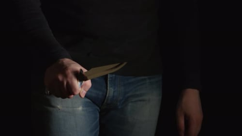 Danger man with a knife comes in the frame from a dark and moves on