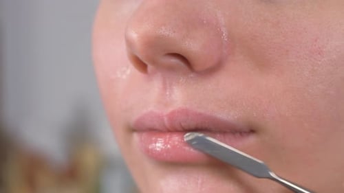 Préparer la peau du modèle pour le maquillage. Traitement des lèvres à l'aide d'une spatule et d'un baume à lèvres Gros plan.