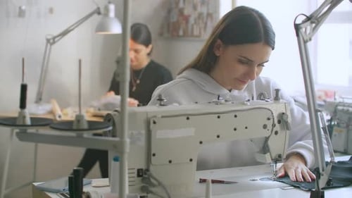 Front View Of Female Fashion Designer Working With Sewing Machine In Workshop