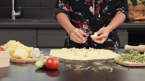 Hands putting cheese on pizza base, making traditional italian cheese pizza