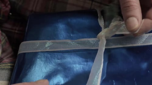 Hand opening gift wrapped in paper close up