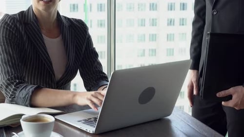 Empresária e empresário se reunindo com um laptop que parece e discutindo juntos.