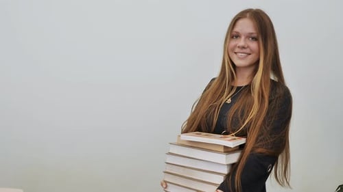 Young Woman Holds Stack of Books and Smiles