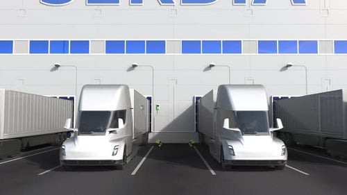 Electric Trucks at Warehouse Dock with PRODUCT OF SERBIA Text