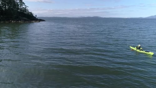 Aerial Reveal Of Man Paddling Kayak Along Ocean Coastline
