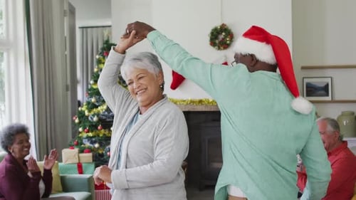 Senior Couple Dancing at Christmas Celebration with Friends