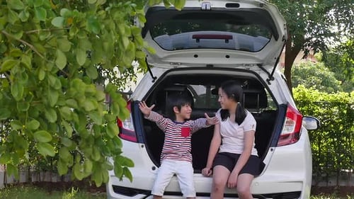 Children Chatting in Car Trunk on Sunny Day