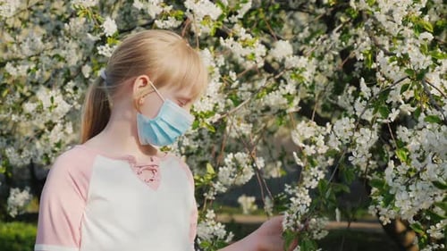 Sad Child in a Mask Near Flowering Trees. Allergy Problem