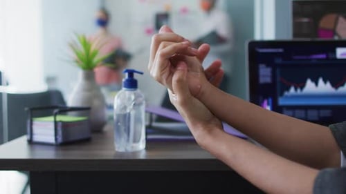 Close up view of woman using hands sanitizer at modern office