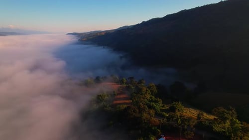 4K aerial view over mountain at sunrise in heavy fog. golden morning sunlight