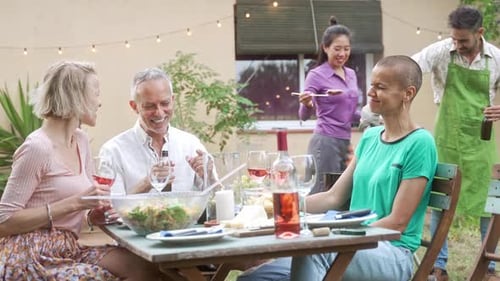Adult Friends Enjoying Outdoor Summer BBQ at Home Garden Cooking and Having Good Times Together