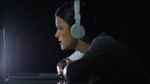 Woman with Headphones Uses Laptop at Night