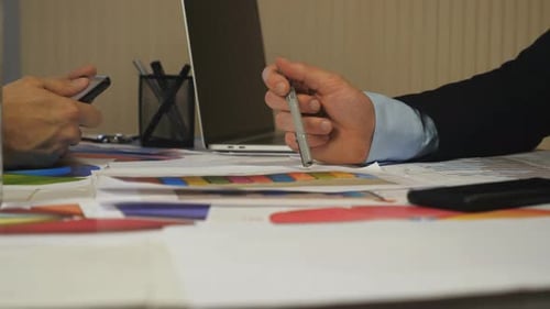 Manos masculinas de dos socios analizando informes financieros en gráficos y tabletas en la oficina