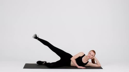 Young Sporty Woman Doing Side Leg Lift Exercise In Studio