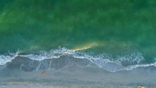 El hombre corre a lo largo de la playa de arena. Vista aérea.