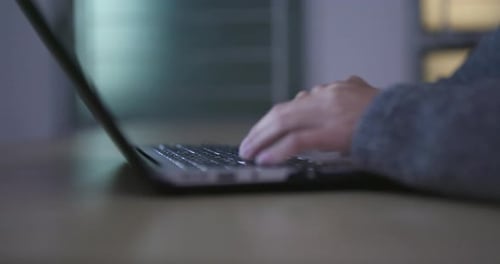 Hands Typing on Laptop Keyboard at Night