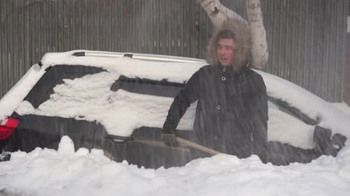 Young Adult shovels snow from around car