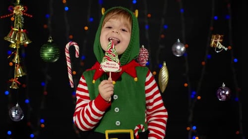 Child in Elf Costume Holds Christmas Lollipop