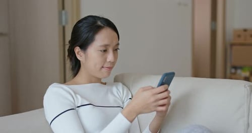 Young Woman Uses Smartphone at Home on Couch