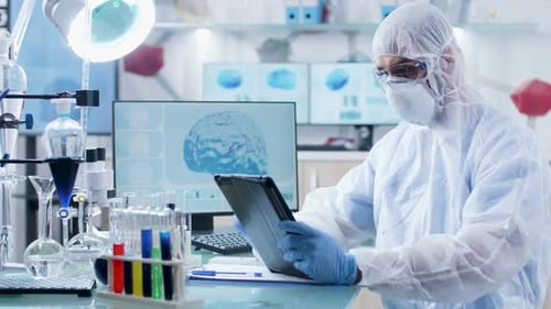 In Modern Laboratory Scientist in Coverall Is Working on a Digital Tablet PC