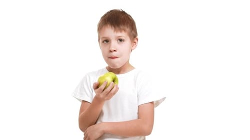 Elementaryschool Aged Caucasian Boy Slowly Eating Big Green Apple Standing on White Background and
