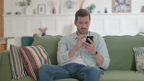 Man Relaxing on Couch Using Smartphone Indoors
