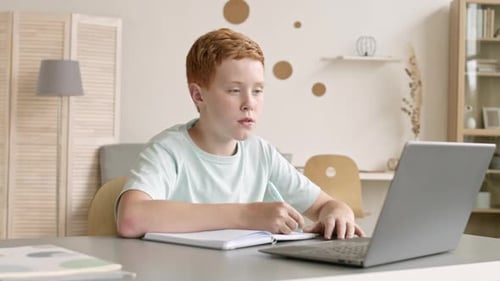 Teenager Sitting at Desk and Doing Home Task