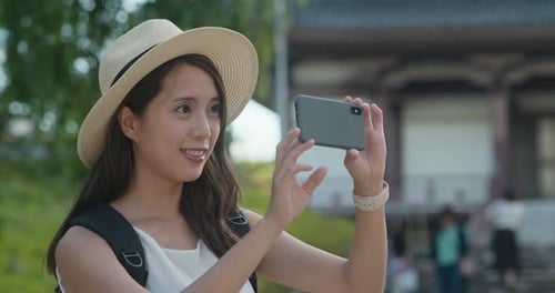 Woman travel in Japan, take photo on mobile phone in the Japanese temple