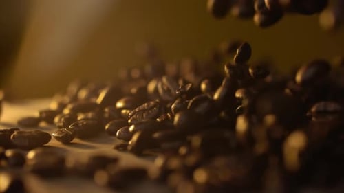 Nahaufnahme von frischen Kaffeebohnen, die in Slowmo auf den Tisch fallen