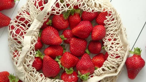 Fresas frescas en paquete ecológico sobre fondo de madera blanca, comida orgánica vegetariana