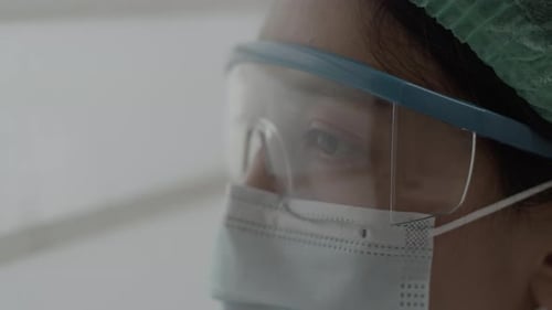 Close-up doctor or nurse exhausted and looking outside a window while resting working in a hospital.