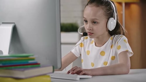 Girl Learning at Computer with Headset and Books