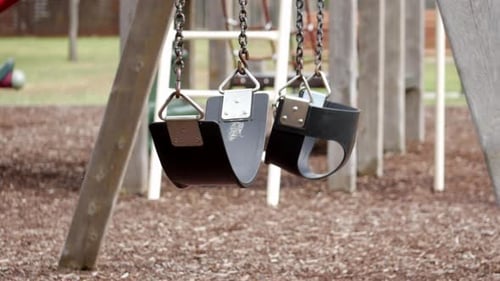 Empty swing set in an empty playground. Swings blowing in the wind.