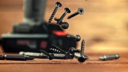 Screws Falling Near Drill on Wood Surface