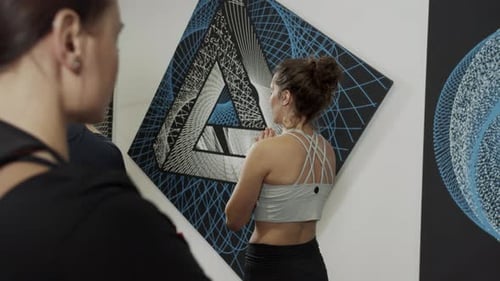 Women Exercising in Fitness Studio with Modern Art