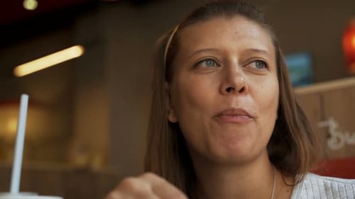 Femme dans un café de restauration rapide manger de la malbouffe