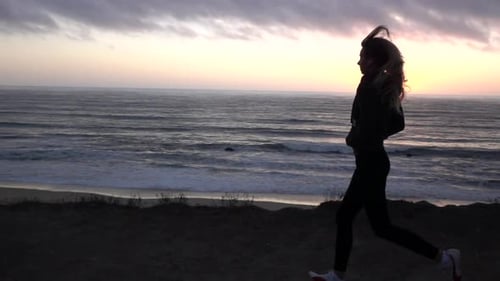 Woman Runs Along Beach During Sunset