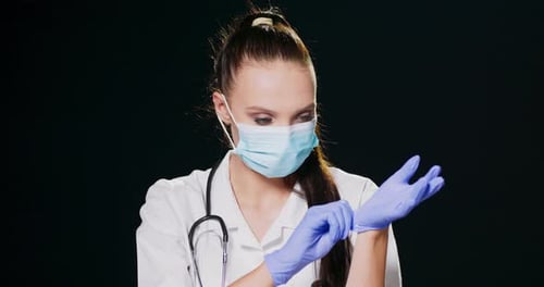 Medical Professional Putting on Gloves Wearing Mask