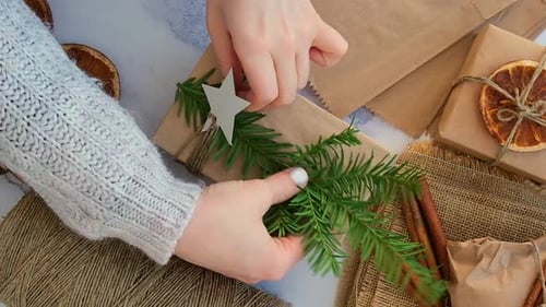 Woman Making Box with New Year's Gifts Wrapped in Craft Paper and Decorated with Fir Branch