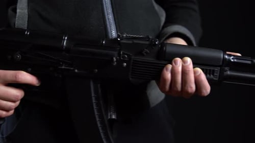 Ein Bandit steht mit einer Waffe in der Hand auf einem schwarzen Hintergrund. Nahaufnahme Panorama von links nach rechts