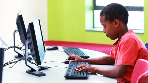 Focused Student Typing at Computer in Classroom