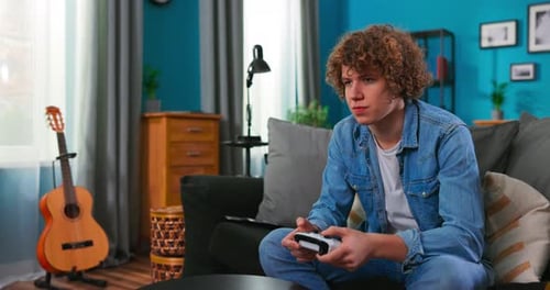 Teen Plays Video Game at Home on Couch